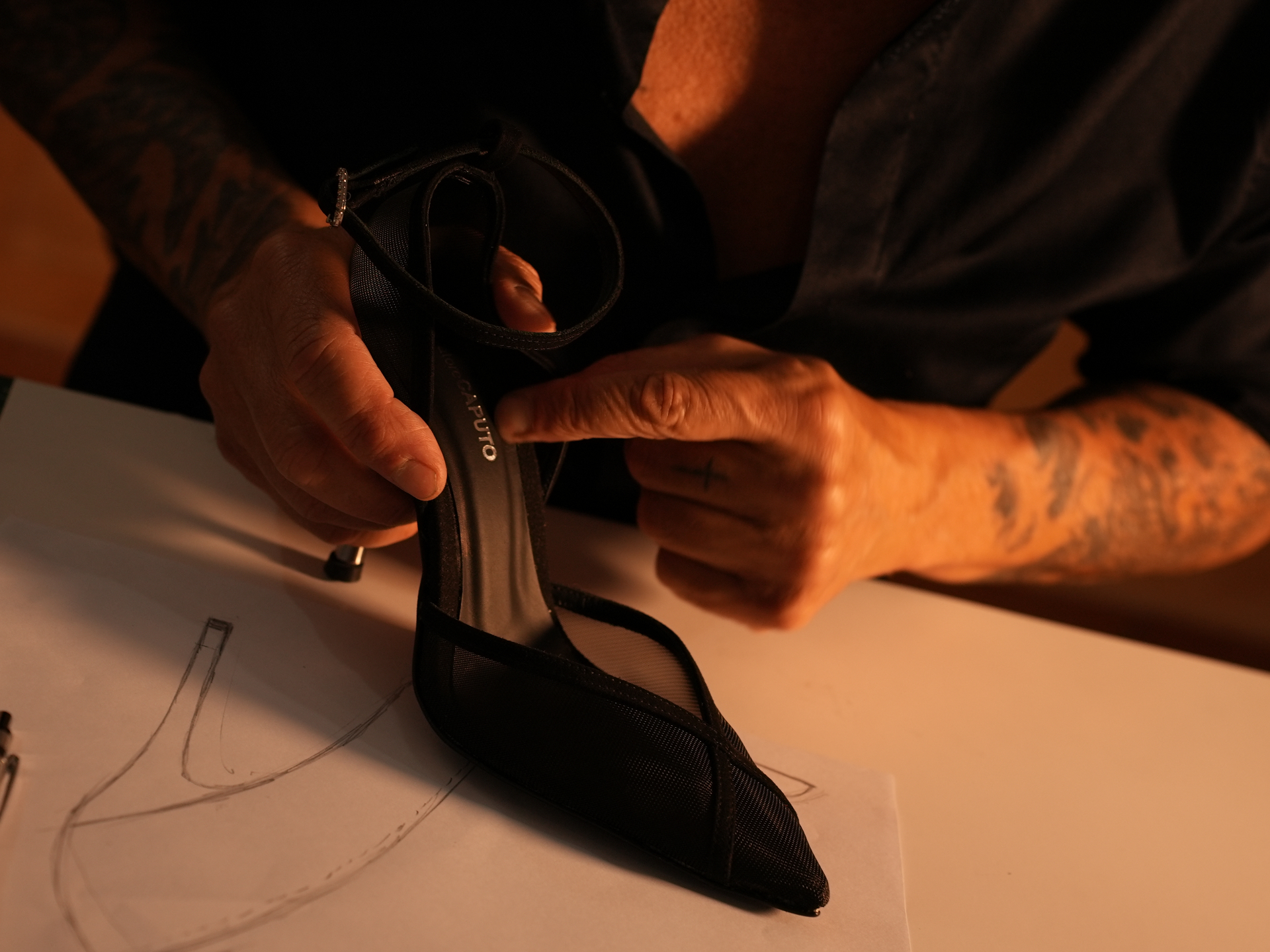Salvatore Caputo rifinisce a mano una scarpa su misura accanto al disegno originale